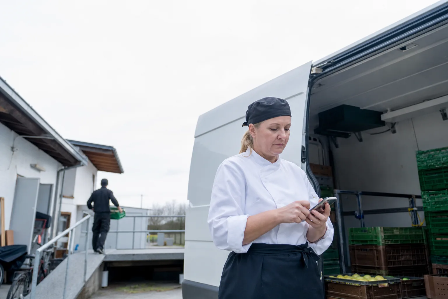 Eine Küchenmitarbeiterin aktualisiert unterwegs einen Wochenplan auf einem Smartphone